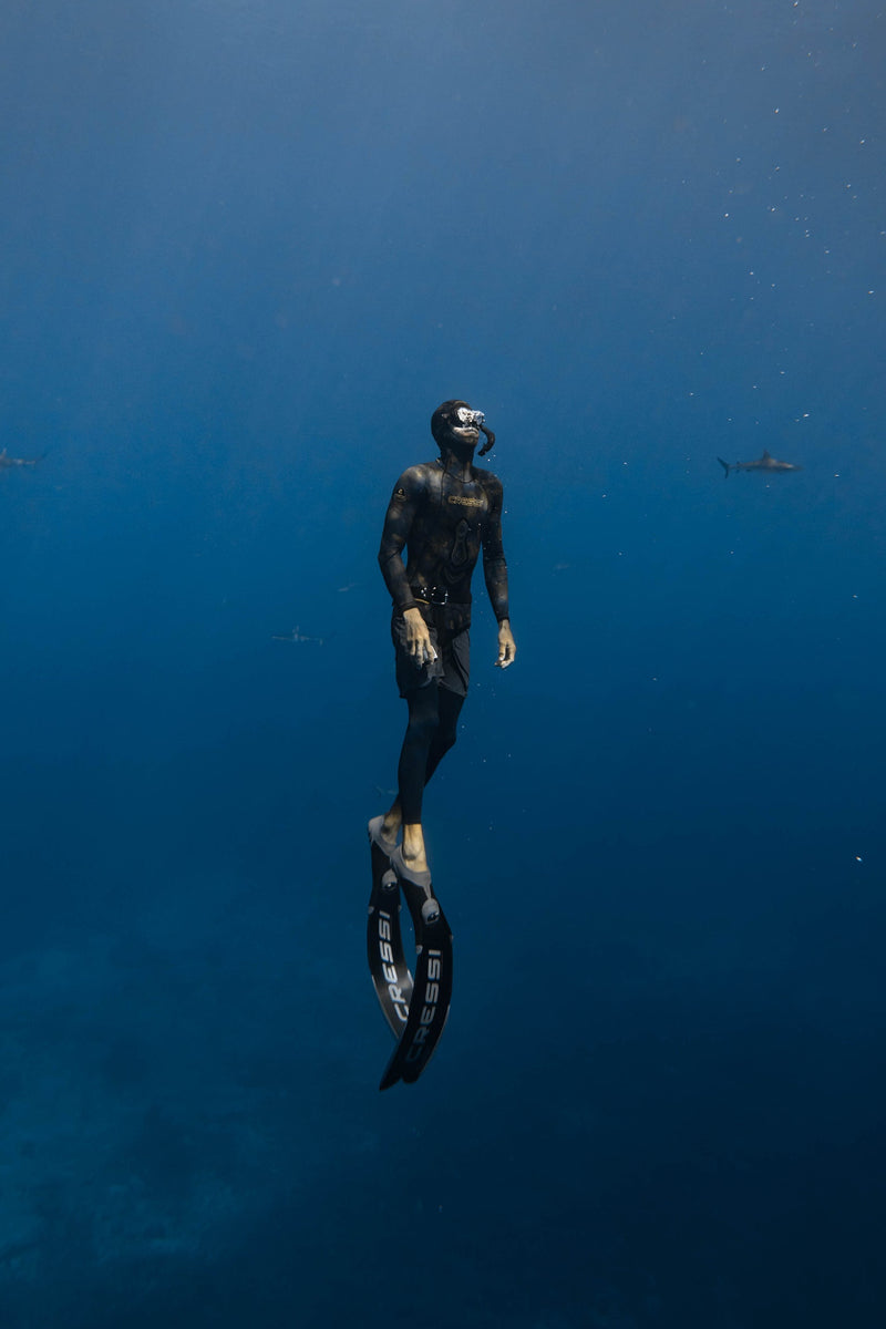 Person freediving in deep blue water with fins